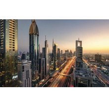 Panoramabild av Dubais skyline med upplysta skyskrapor och vägtrafik i skymningen.