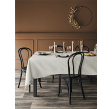 Matbord med dukning, stolar och en blommig krans på väggen i en matsal.