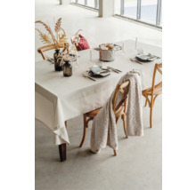 Dukat matbord med duk, porslin, dekoration och stolar.