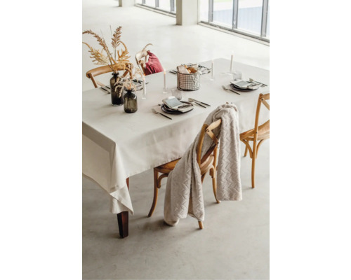 Dukat matbord med duk, porslin, dekoration och stolar.