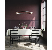 Matbord med bordsservis, stolar och en ringformad hänglampa i en matsal.