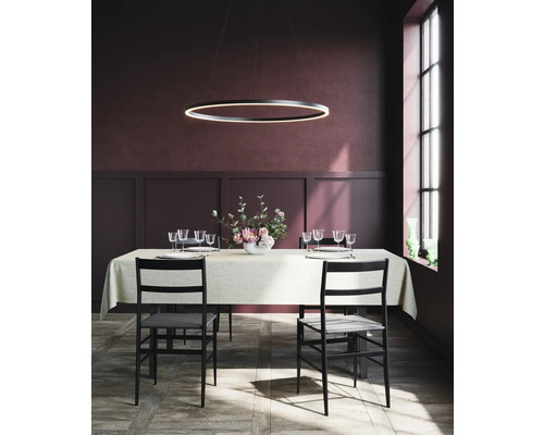 Matbord med bordsservis, stolar och en ringformad hänglampa i en matsal.