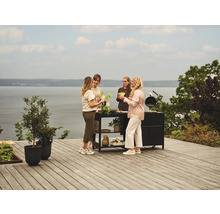 Grupp av personer står på en terrass med ett grillbord och blomlådor