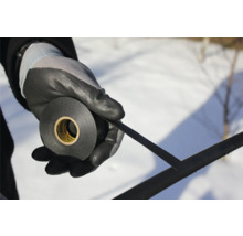 En person håller en rulle isoleringstejp med arbetshandskar.