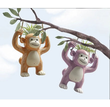 Två hängande krukor i form av apor på en gren