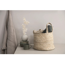 Dekorativ scen med korg, handduk och vas på ett bord