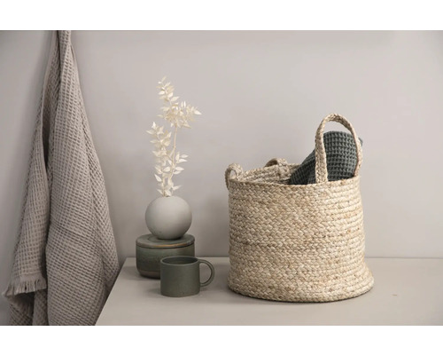 Dekorativ scen med korg, handduk och vas på ett bord