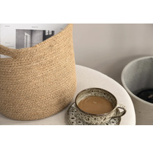 Dekorativ scen med jutekorg, kaffekopp och tidning på ett bord