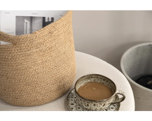 Dekorativ scen med jutekorg, kaffekopp och tidning på ett bord