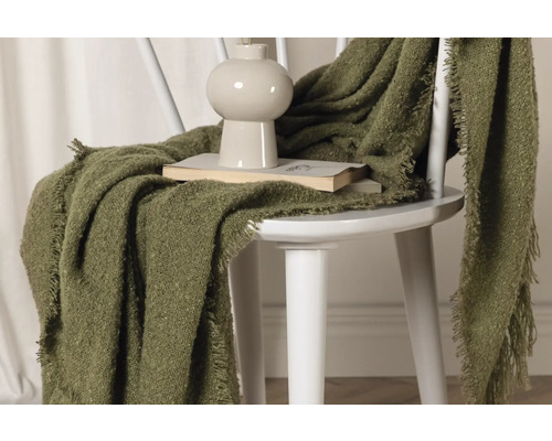 Grön filt på en stol med bok och vas