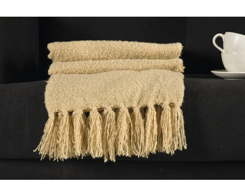 Beige överkast med fransar på en soffa