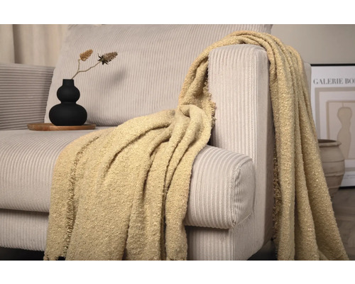 Detaljbild av en soffa med manchestertyg och en dekorativ filt.