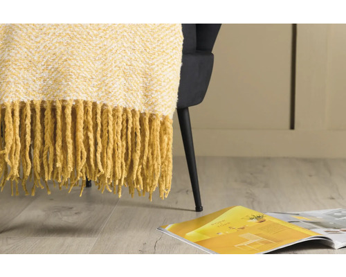 Gul sängöverkast med fransar på en fåtölj