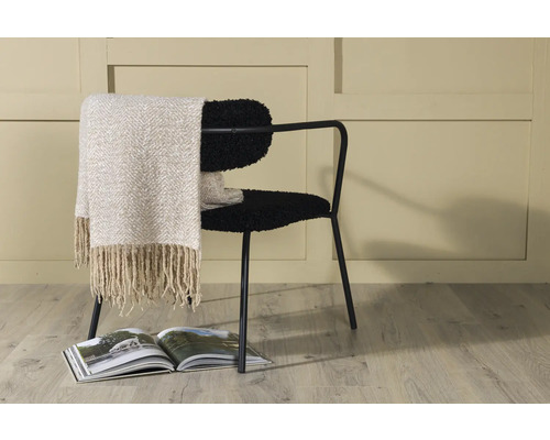 Inredningsexempel med en stol, en filt och en bok.