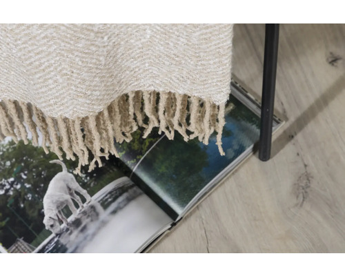 Beige överkast med fransar på tidningen