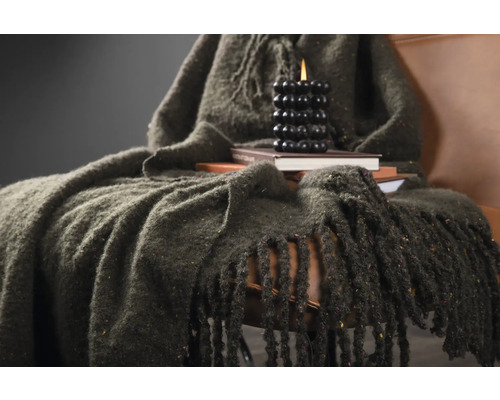 Dekorativt stilleben med en filt, böcker och ett ljus