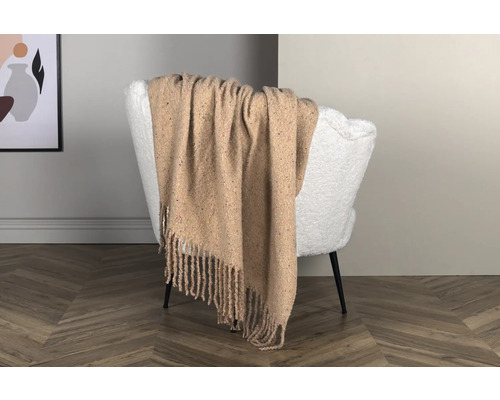 Beige filt med fransar på vit fåtölj