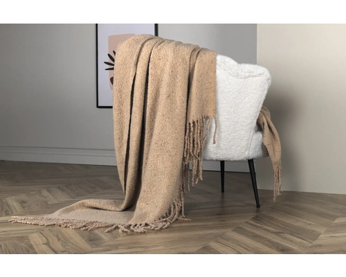 Beige filt med fransar draperad över en fåtölj