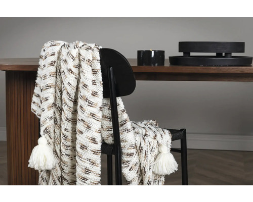 Dekorativt överkast med tofsar draperat över en stol