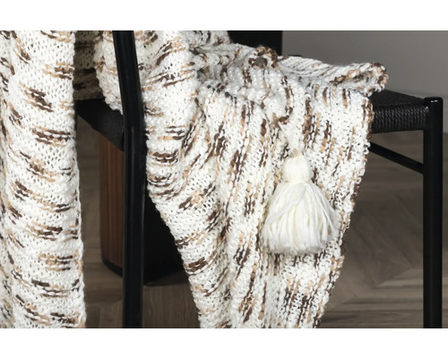 Dekorativ stickad filt med tofs på en stol