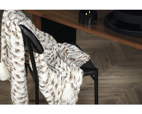 Grovstickad pläd med tofsar på en stol