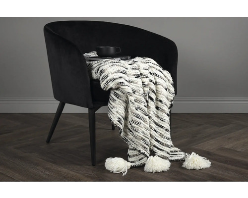 Fåtölj med stickad filt, bok och kopp