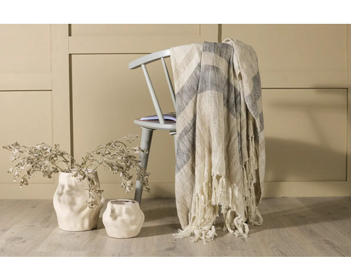 Dekorativ scen med stol, pläd och vaser med grenar