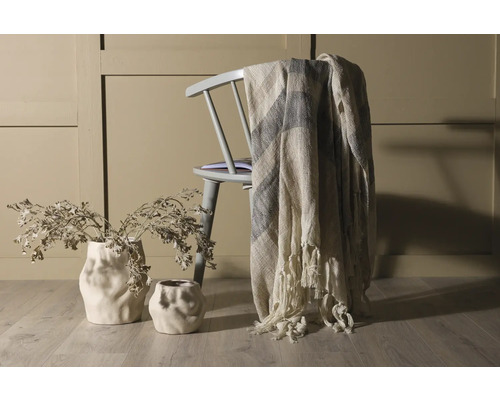 Scen med stol, filt och vaser med torkade blommor för en ljus och organiserad atmosfär i rummet.