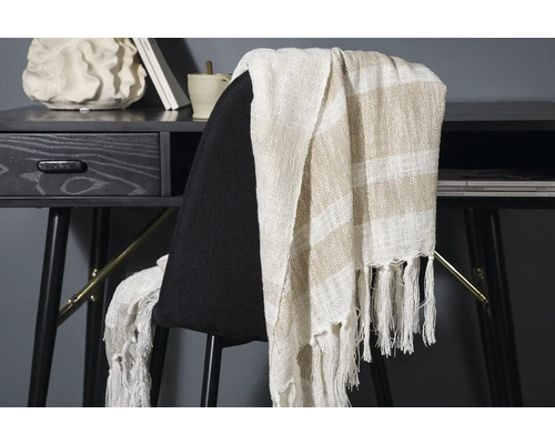 Dekorativt överkast med randigt mönster och fransar på en stol