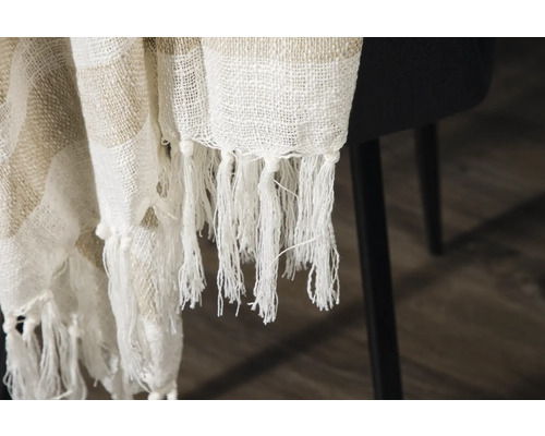 Dekorativt tyg med fransar ligger på en stol