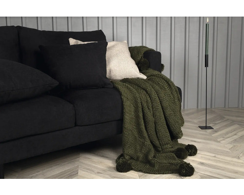 Svart soffa med kuddar och överkast samt ljusstake