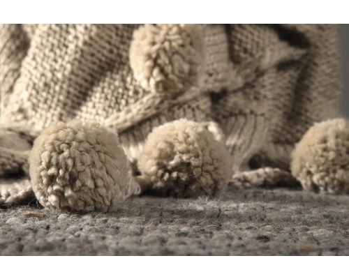 Närbild av en stickad halsduk med tofsar