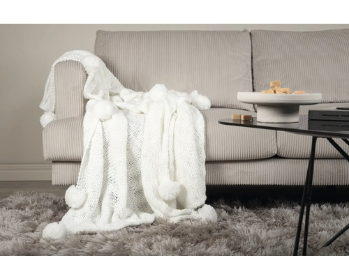 Dekorativt vardagsrum med soffa, matta och filt med tofsar