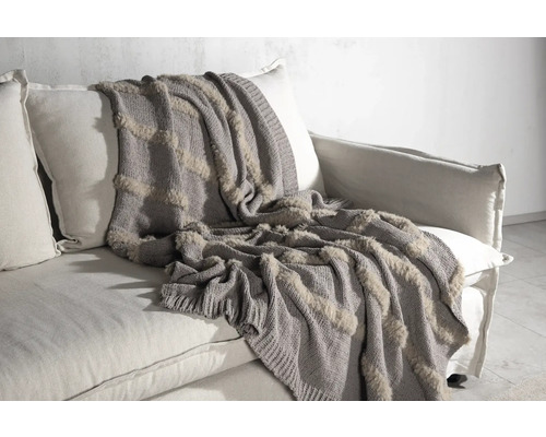 Grå stickad filt med fuskpäls på soffa