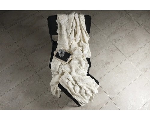 Dekorativ filt på en stol med böcker och dricksglas