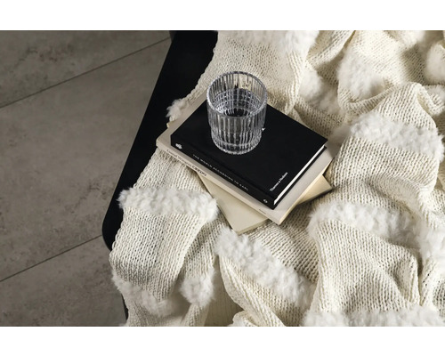 Stilleben med ullfilt, böcker och glas på ett bord