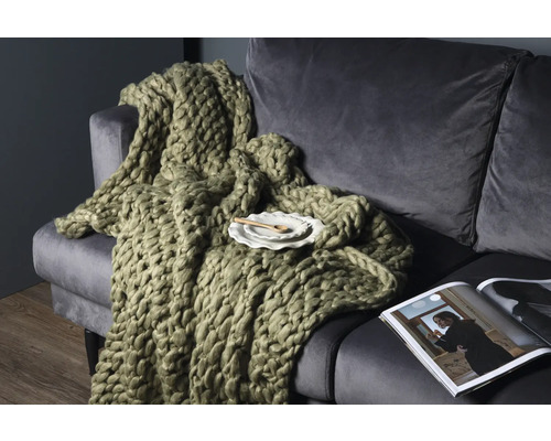 Stor stickad filt på en soffa med tidning och tallrik