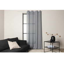 Vardagsrum med gardin framför fönstret, soffa och sidobord.