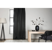 Ljust rum med svart gardin, golvlampa, bord och stol.