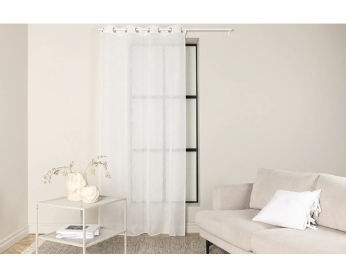 Ljust vardagsrum med fönster, gardin, bord och soffa