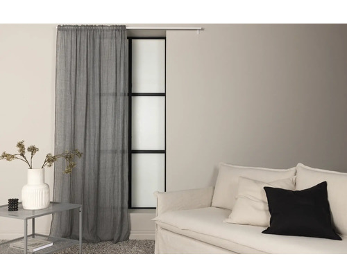 Vardagsrum med soffa, sidobord, dekoration och gardin framför fönstret