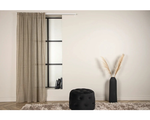 Vardagsrum med gardin, fönster, pall och vas på en matta.