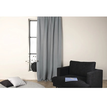 Vardagsrum med gardin framför fönstret och fåtölj