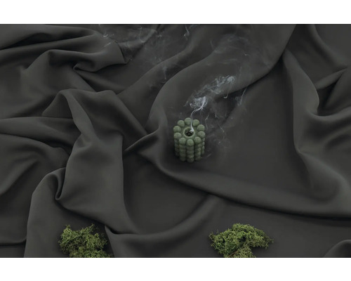 Dekorativt grönt ljus med rökutveckling på mörkt tyg