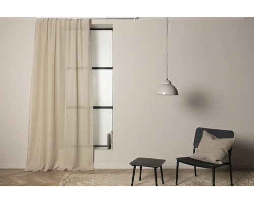 Vardagsrum med gardin, stol och lampa för en mysig atmosfär.