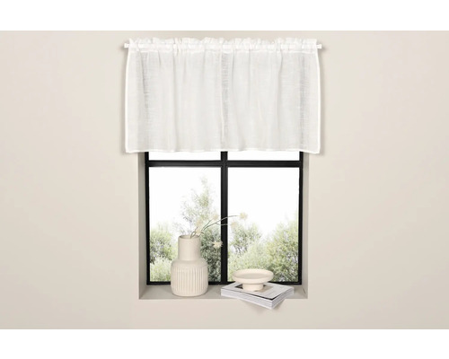 Gardin framför ett fönster med dekorationer på fönsterbrädan