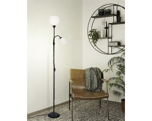 Golvlampa med två lampor bredvid en fåtölj och en vägghylla