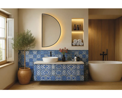 Badrum med tvättställ, spegel, badkar och blått kakel med mönster