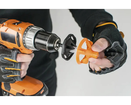 En borrmaskin med ett borrskruvstillbehör för slipning hålls av en person.