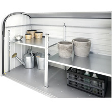 Invändig vy av ett trädgårdsskjul med hyllor och trädgårdstillbehör som vattenkannor och blomkrukor.